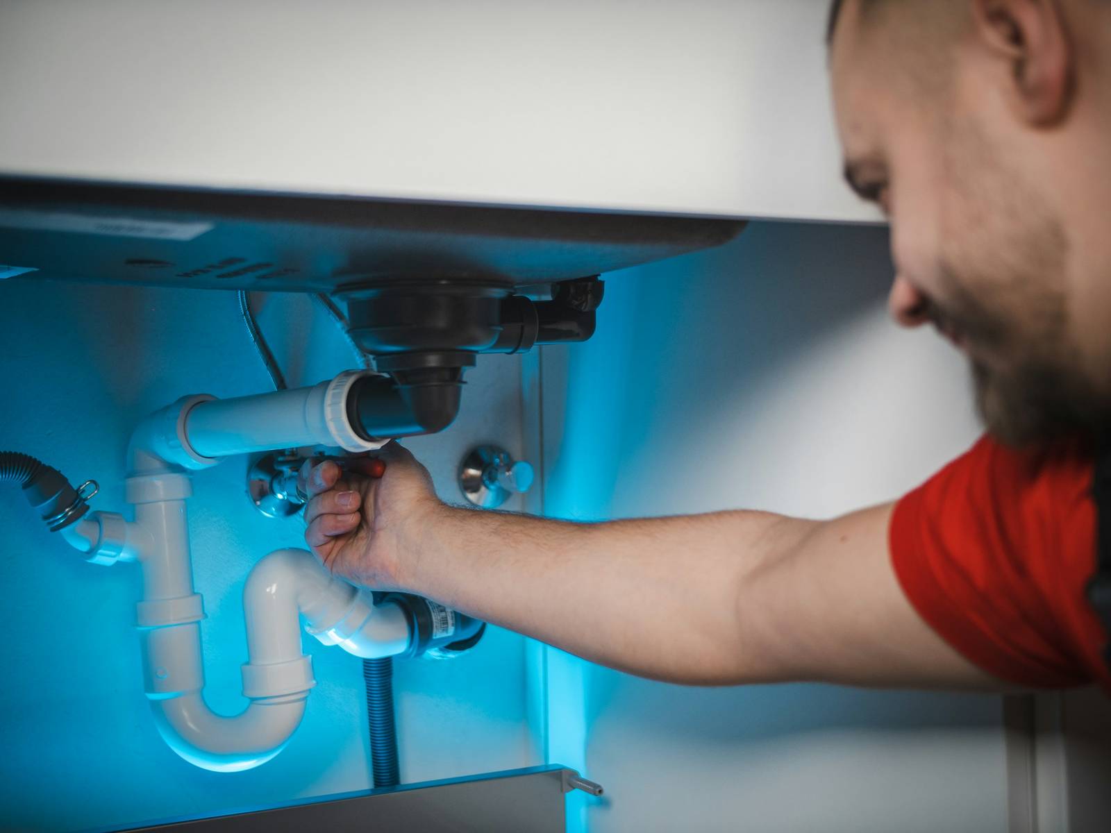 Plumber reaching under a sink to adjust the drain assembly